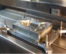 Machined mold cavity workpiece clamped on a VMC table during hard milling (customer-site trial photo, not a certificate)