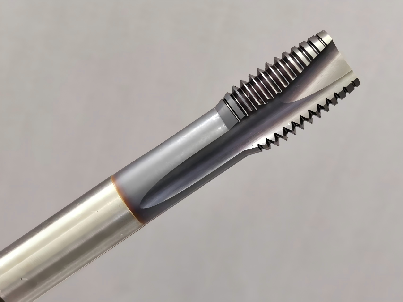 Close-up photograph of a multi-form thread milling cutter showing axial thread teeth and a chip flute